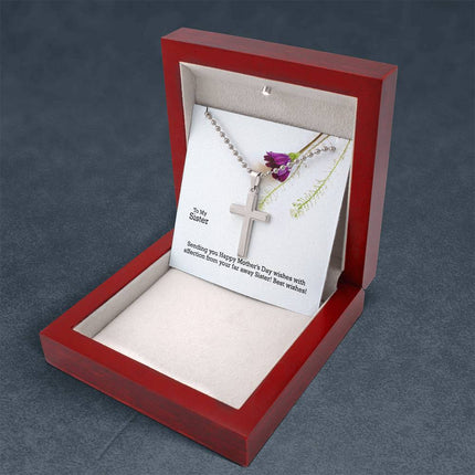 Polished stainless steel cross necklace with ball chain displayed in a luxury gift box with a To My Sister Sending Happy Mother's Day Wishes message card and purple wildflower background.