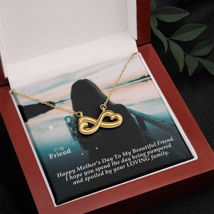 Heart-shaped infinity endless love necklace in white gold finish held in hands, displayed in a gift box with a To My Friend Happy Mother's Day message card and moody teal sunset background.