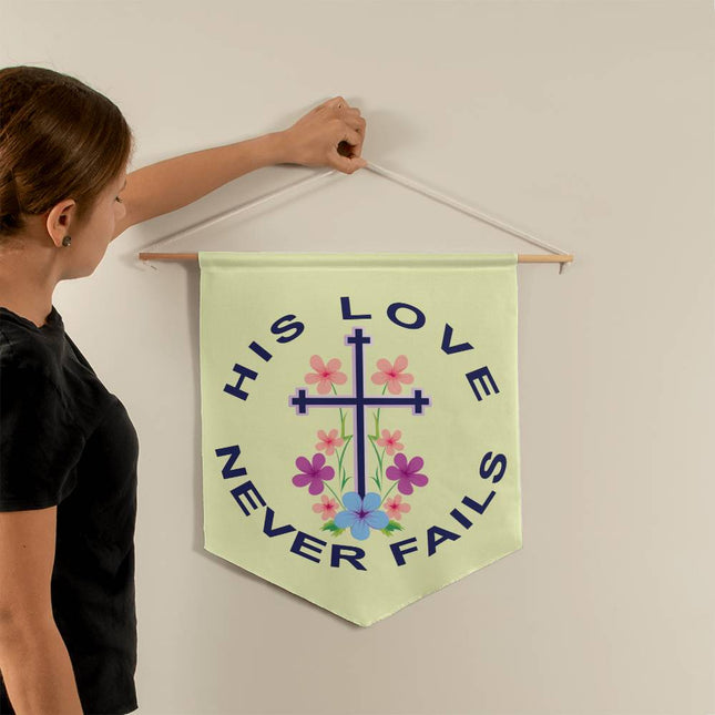 His love never fails wall pennant with floral cross and curved navy text on light green background – 21x18 Christian wall decor