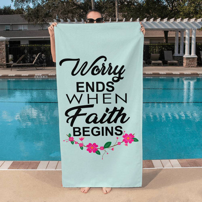 Worry ends when faith begins bath towel with black lettering and pink floral accents on light blue background – 60x30 Christian beach towel