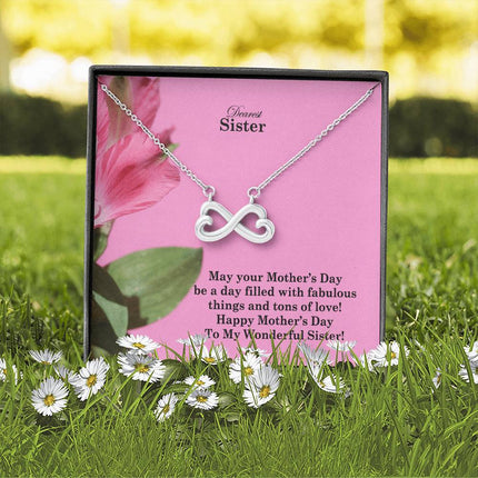 Heart-shaped infinity endless love necklace in white gold finish held in hands, displayed in a gift box with a Dearest Sister Happy Mother's Day message card on a pink floral background.