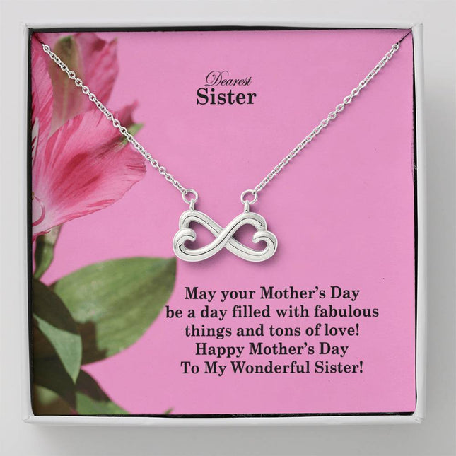 Heart-shaped infinity endless love necklace in white gold finish held in hands, displayed in a gift box with a Dearest Sister Happy Mother's Day message card on a pink floral background.