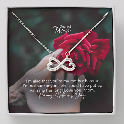 Heart-shaped infinity endless love necklace in white gold finish held in hands, displayed in a gift box with a My Dearest Mom Happy Mother's Day message card and red rose background.