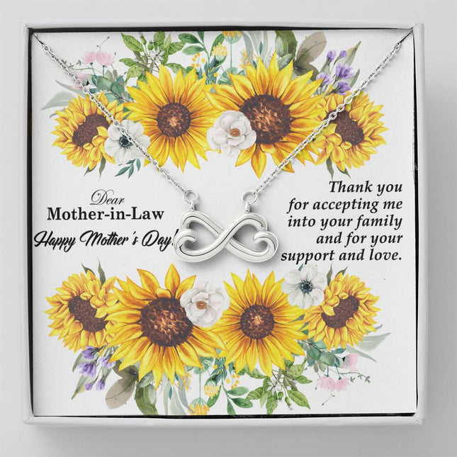 Heart-shaped infinity endless love necklace in white gold finish held in hands, displayed in a gift box with a Dear Mother-in-Law Happy Mother's Day message card and sunflower floral background.