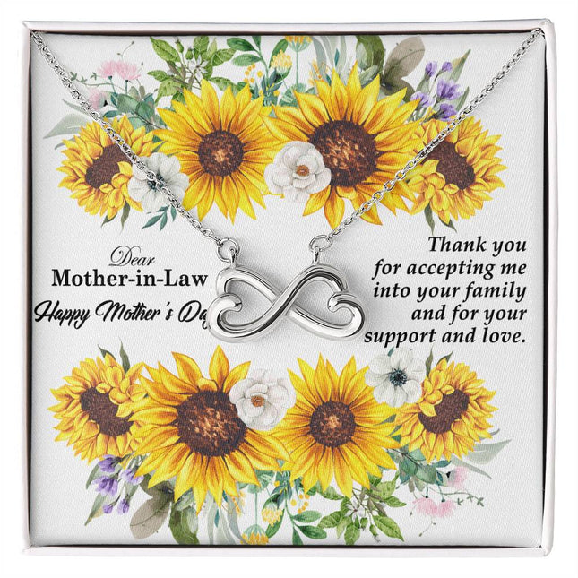Heart-shaped infinity endless love necklace in white gold finish held in hands, displayed in a gift box with a Dear Mother-in-Law Happy Mother's Day message card and sunflower floral background.