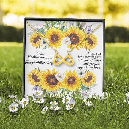 Heart-shaped infinity endless love necklace in white gold finish held in hands, displayed in a gift box with a Dear Mother-in-Law Happy Mother's Day message card and sunflower floral background.