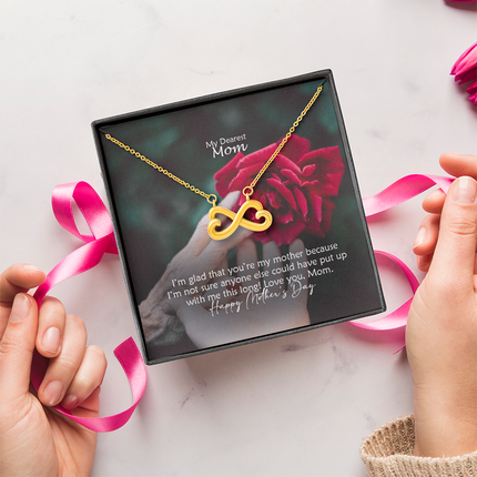Heart-shaped infinity endless love necklace in white gold finish held in hands, displayed in a gift box with a My Dearest Mom Happy Mother's Day message card and red rose background.