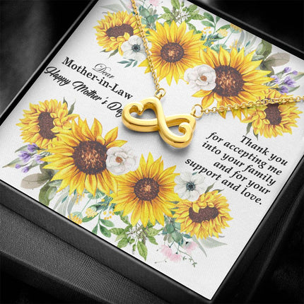 Heart-shaped infinity endless love necklace in white gold finish held in hands, displayed in a gift box with a Dear Mother-in-Law Happy Mother's Day message card and sunflower floral background.