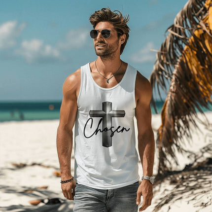 Man wearing a white unisex tank top featuring a silver chrome 3D cross graphic with the word "Chosen" in black script on the front, styled on a sunny beach setting.