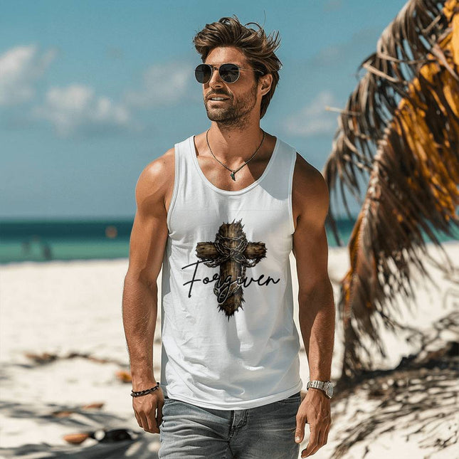 Man wearing a white unisex tank top featuring a wooden cross wrapped with a crown of thorns and chains with the word "Forgiven" in black script on the front, styled on a sunny beach setting.