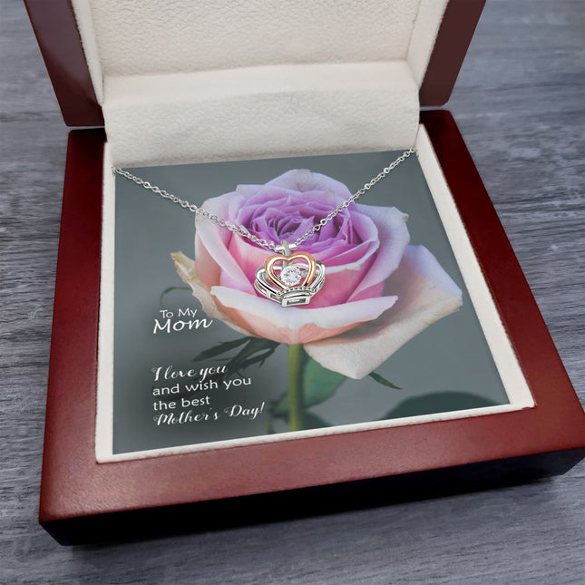 Sterling silver and rose gold crown pendant necklace with a sparkling cubic zirconia center, displayed in a mahogany luxury LED gift box with a To My Mom I Love You Happy Mother's Day message card and a pink rose background.
