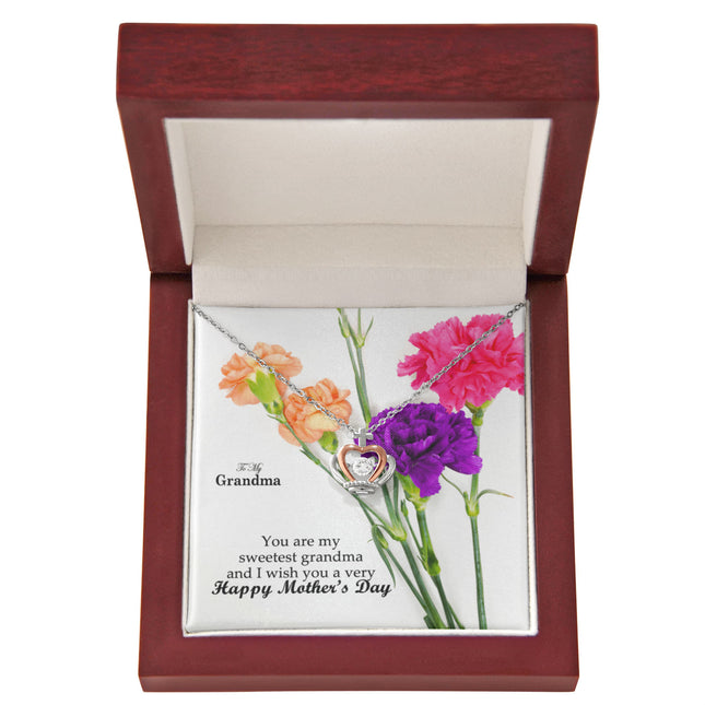 Sterling silver and rose gold crown pendant necklace with a sparkling cubic zirconia center, displayed in a mahogany luxury LED gift box with a To My Grandma Happy Mother's Day message card and colorful carnation flowers.