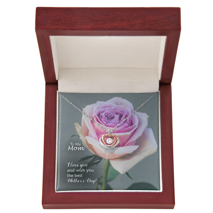 Sterling silver and rose gold crown pendant necklace with a sparkling cubic zirconia center, displayed in a mahogany luxury LED gift box with a To My Mom I Love You Happy Mother's Day message card and a pink rose background.